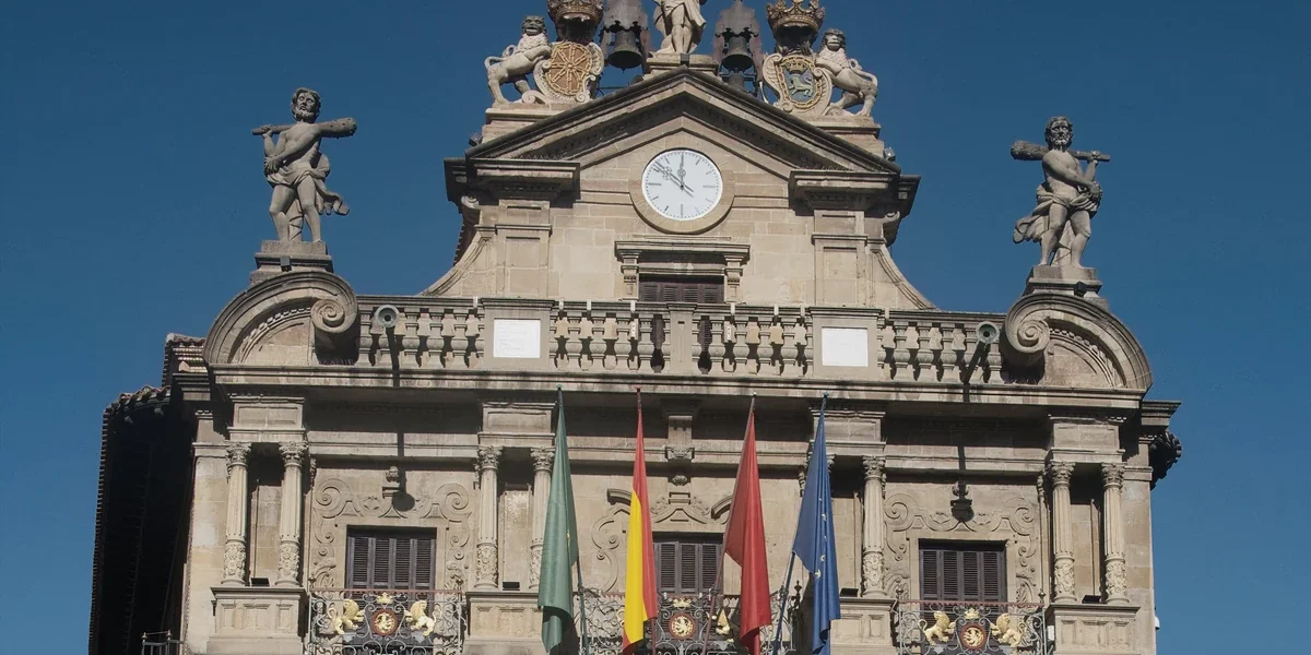 pamplona-ayuntamiento-busqueda-local-desktop-v3 Fachada del Ayuntamiento de Pamplona con su reloj y banderas
