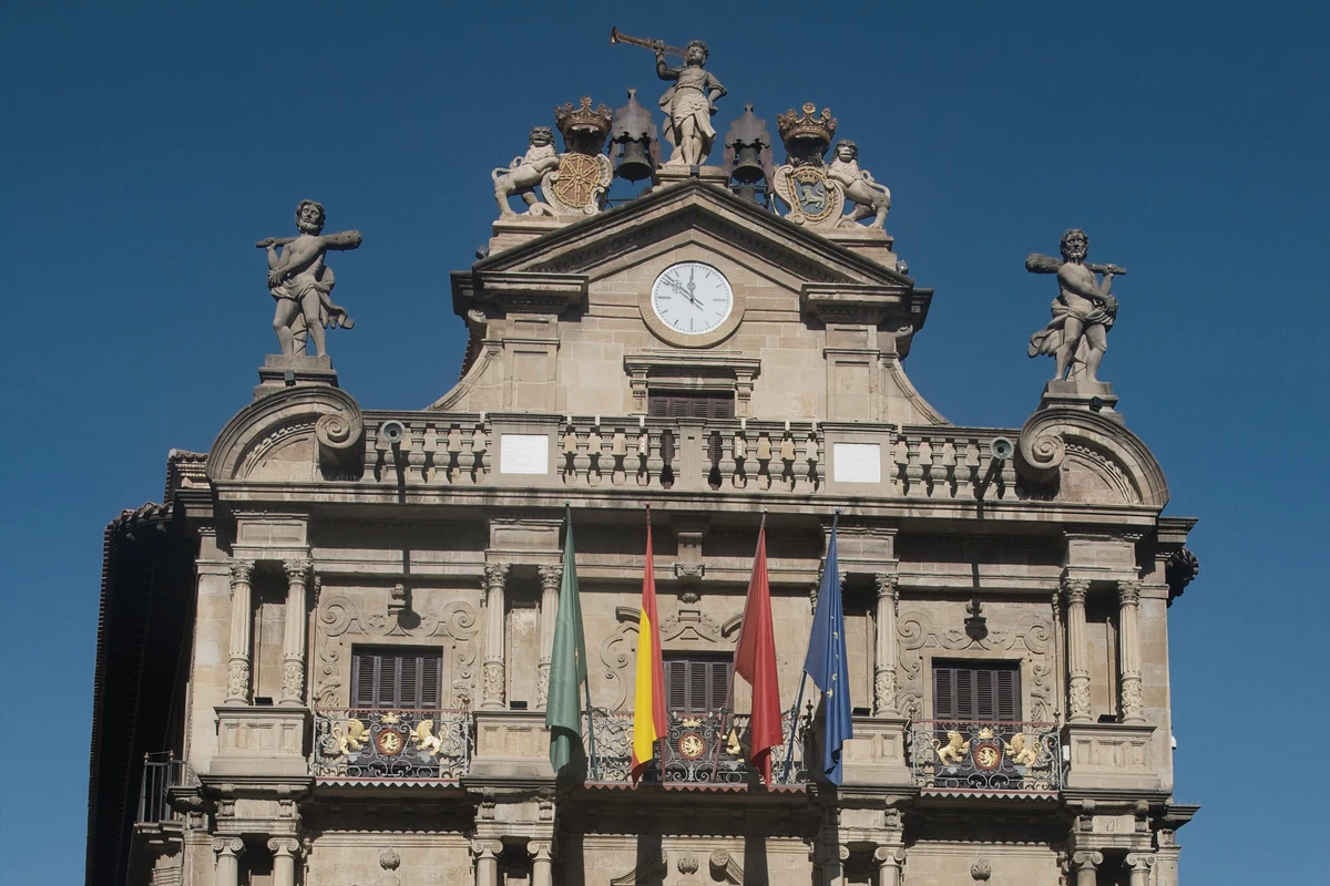 Fachada del Ayuntamiento de Pamplona con su reloj y banderas