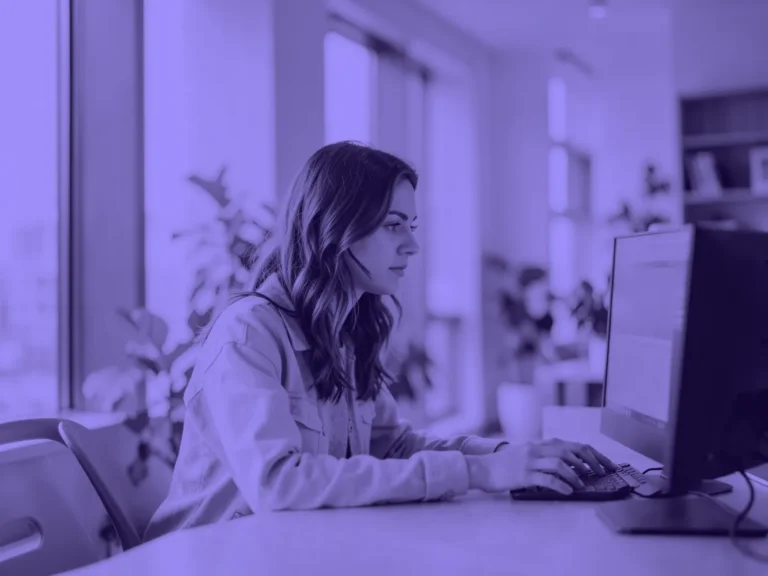 Diseñadora trabajando concentrada ante un monitor en un estudio luminoso con plantas