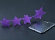 Cinco estrellas de papel violeta en fila junto a un móvil boca abajo, la idea de sumar reseñas en Google