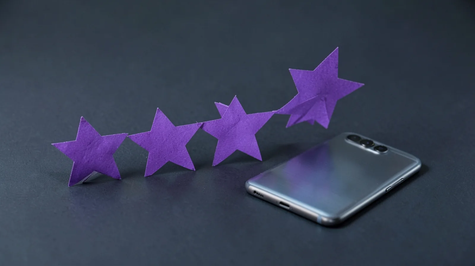 Cinco estrellas de papel violeta en fila junto a un móvil boca abajo, la idea de sumar reseñas en Google