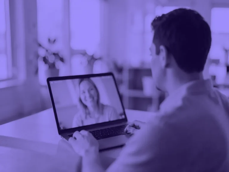 Hombre de espaldas en una videollamada desde su portátil, con una mujer sonriente en la pantalla