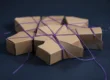 Cajas de cartón kraft agrupadas sobre la mesa y unidas entre sí por hilos violetas tensos