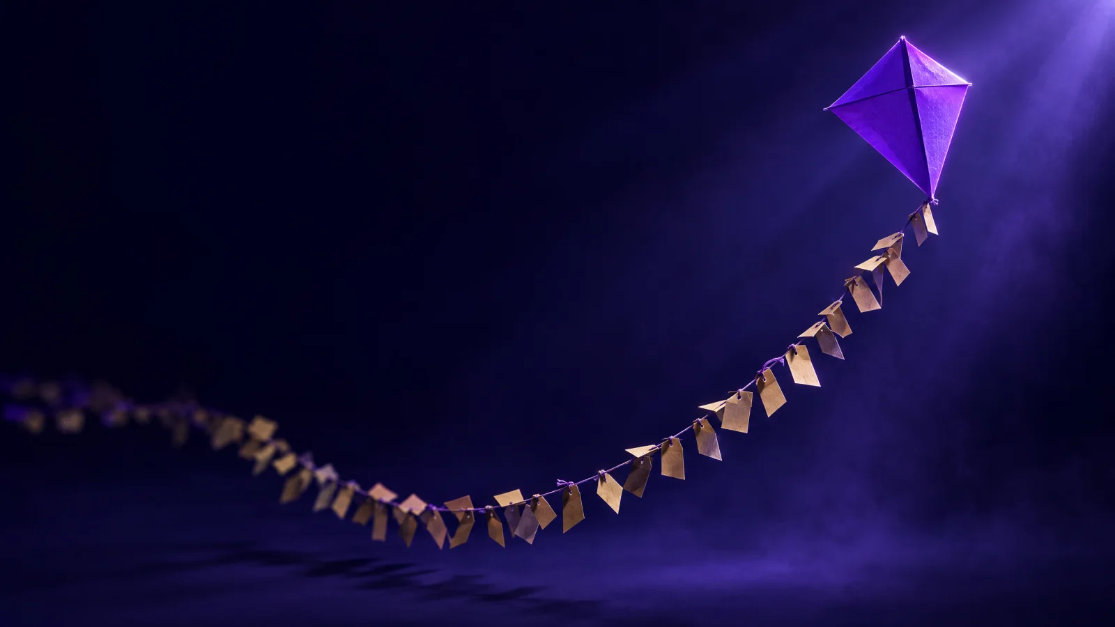 Cometa de papel violeta con una cola larguísima de pequeñas etiquetas kraft, como las búsquedas long tail