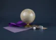 Globo terráqueo de mesa con una cinta violeta a su lado y dos adaptadores de enchufe de viaje